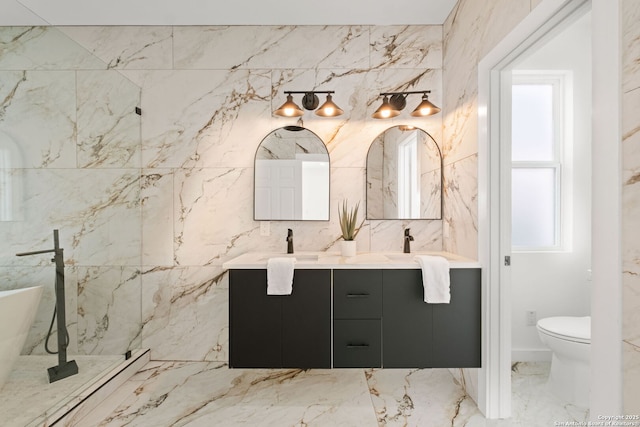full bath featuring double vanity, a healthy amount of sunlight, toilet, and marble finish floor