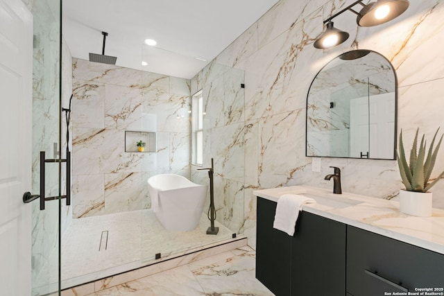 full bath with vanity, a marble finish shower, marble finish floor, a freestanding tub, and tile walls