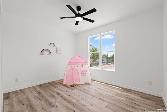 recreation room with baseboards, a ceiling fan, and wood finished floors