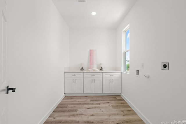 laundry area featuring baseboards, light wood-type flooring, hookup for an electric dryer, cabinet space, and washer hookup