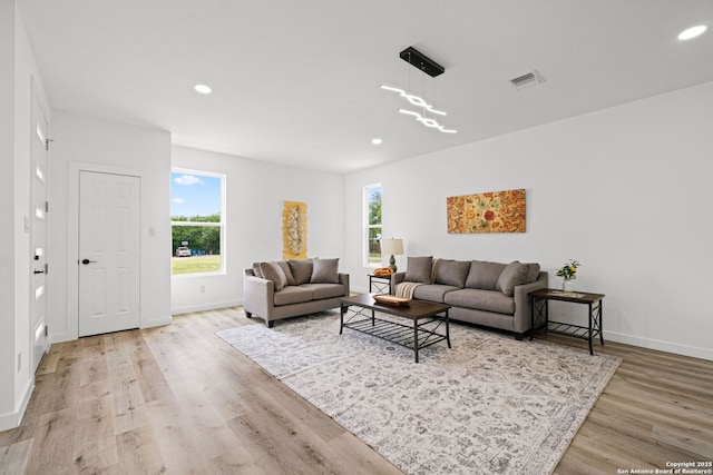 living room featuring light wood-style floors, baseboards, recessed lighting, and visible vents