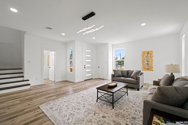 living area featuring visible vents, recessed lighting, light wood-style floors, and stairs
