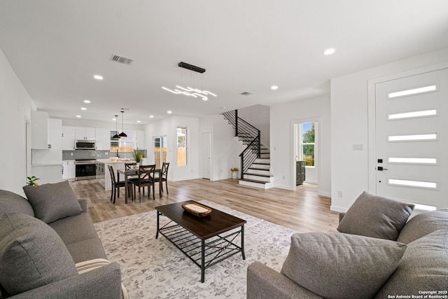 living area with light wood finished floors, recessed lighting, baseboards, visible vents, and stairway