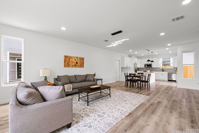 living room featuring light wood-style floors, baseboards, and recessed lighting