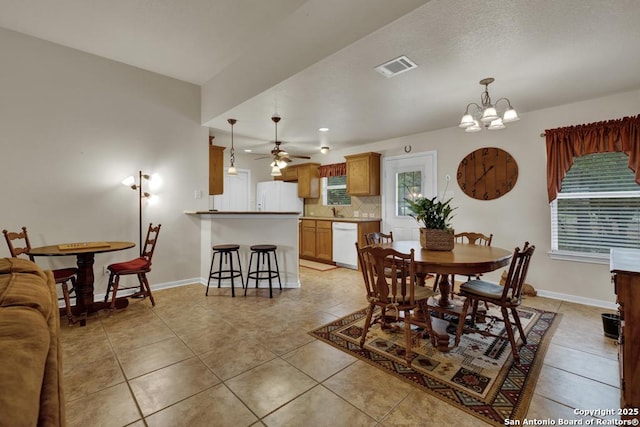 dining room with light tile patterned flooring, ceiling fan with notable chandelier, baseboards, and visible vents