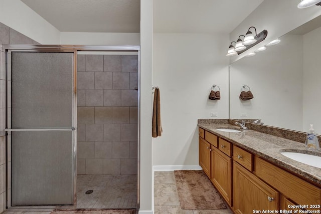 bathroom with a sink, double vanity, baseboards, and a tile shower