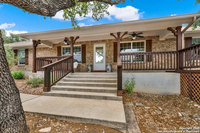 entrance to property featuring covered porch, brick siding, and ceiling fan