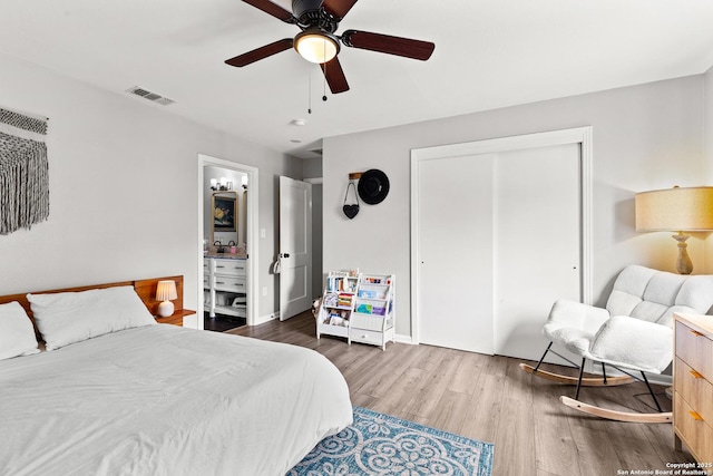 bedroom with a closet, wood finished floors, visible vents, ceiling fan, and baseboards