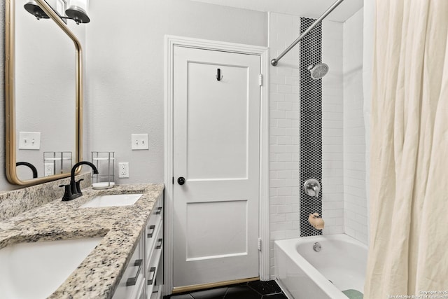 bathroom featuring double vanity, a textured wall, shower / bath combo, and a sink
