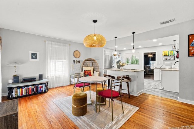 dining room with light wood finished floors, visible vents, baseboards, and recessed lighting