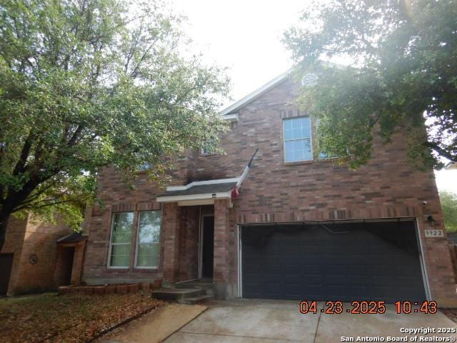 traditional home with driveway, brick siding, and a garage