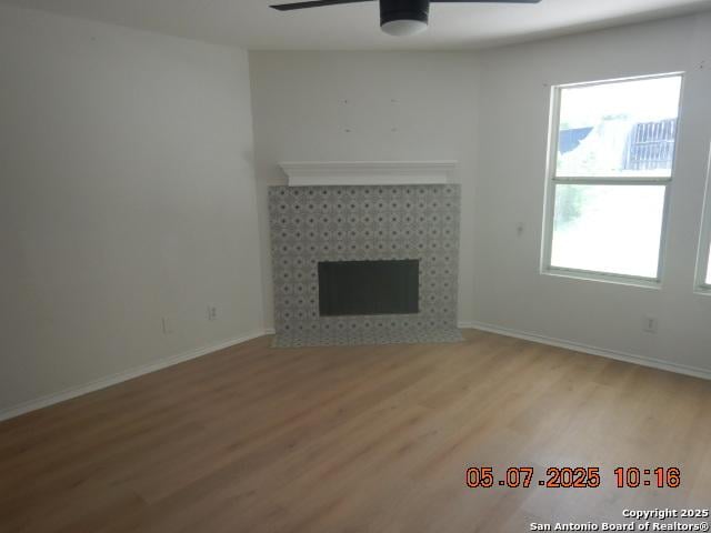 9922 Dull Knife Way, San Antonio, TX 78239 - unfurnished living room with a ceiling fan, light wood-type flooring, a fireplace, and baseboards