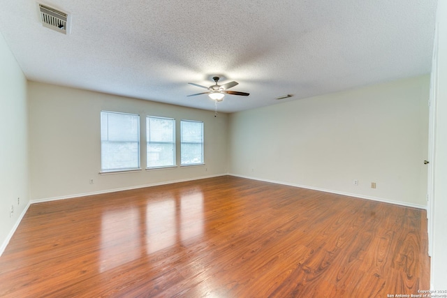 unfurnished room with a textured ceiling, visible vents, wood finished floors, and ceiling fan