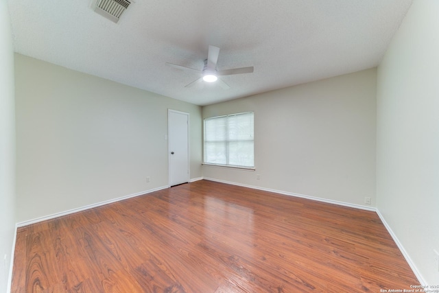 empty room featuring baseboards, a ceiling fan, visible vents, and wood finished floors