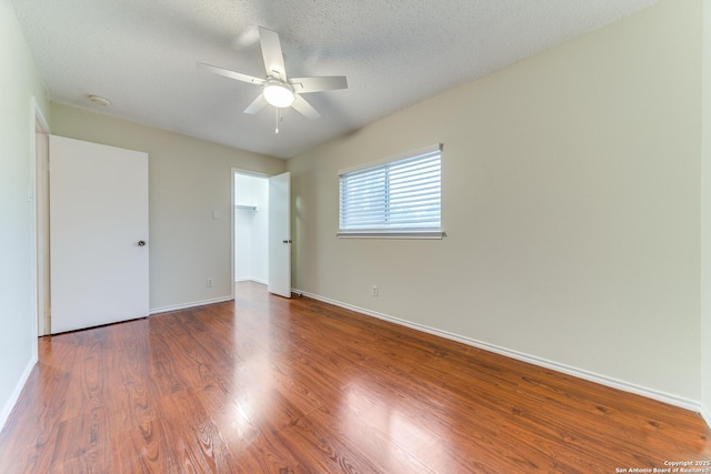 unfurnished bedroom with a textured ceiling, baseboards, a ceiling fan, and wood finished floors
