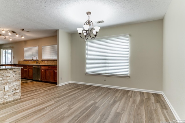 interior space with a chandelier, dishwasher, a textured ceiling, and visible vents