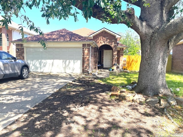 single story home with concrete driveway, brick siding, an attached garage, and fence