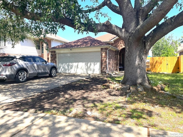 view of front of property with fence, concrete driveway, an attached garage, and brick siding