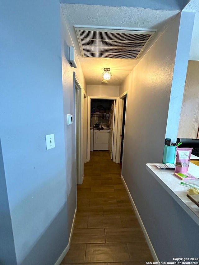 hallway with washing machine and dryer, baseboards, and visible vents