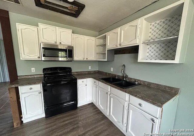 1107 Willow, Jourdanton, TX 78026 - kitchen featuring a sink, dark countertops, black range with electric stovetop, white cabinetry, and stainless steel microwave