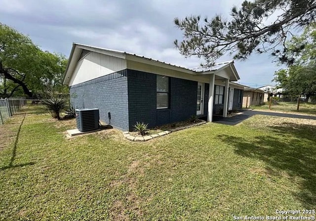 1107 Willow, Jourdanton, TX 78026 - view of side of home featuring fence, cooling unit, brick siding, and a lawn