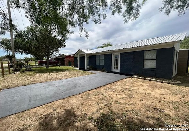 1107 Willow, Jourdanton, TX 78026 - ranch-style home featuring metal roof, brick siding, and driveway