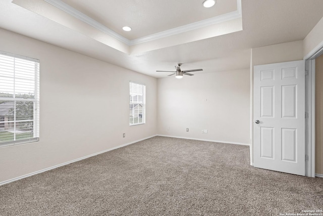 empty room with ornamental molding, carpet flooring, baseboards, and a raised ceiling
