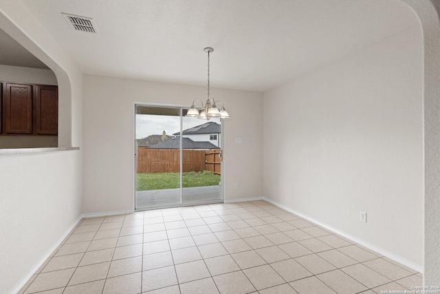 spare room featuring light tile patterned flooring, visible vents, arched walkways, a notable chandelier, and baseboards