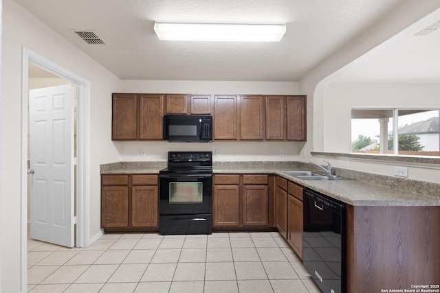 kitchen featuring light tile patterned floors, black appliances, visible vents, and a sink