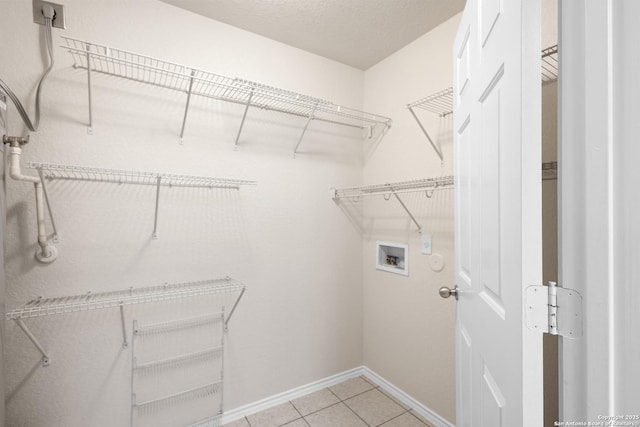 clothes washing area with light tile patterned floors, baseboards, laundry area, and washer hookup