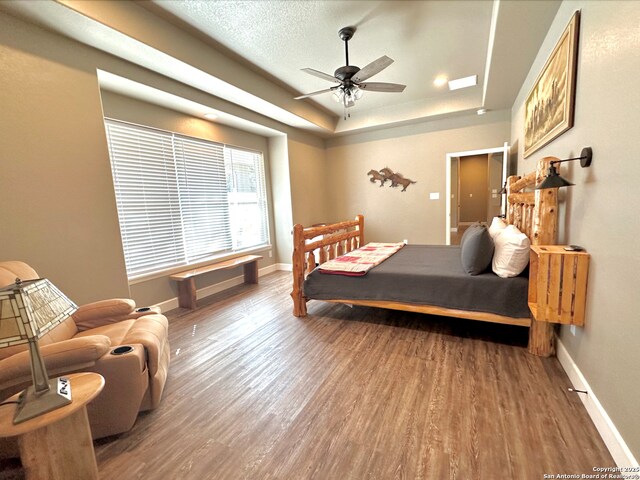181 Crazy Horse, Canyon Lake, TX 78133 - bedroom featuring wood finished floors, baseboards, a tray ceiling, and a ceiling fan