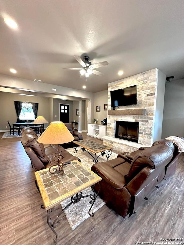living room with wood finished floors, a ceiling fan, a fireplace, visible vents, and recessed lighting