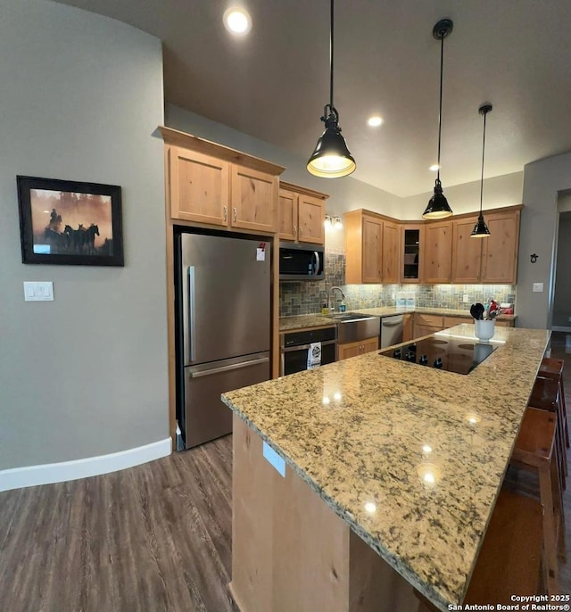 kitchen featuring a center island, stainless steel appliances, dark wood finished floors, light stone countertops, and decorative backsplash