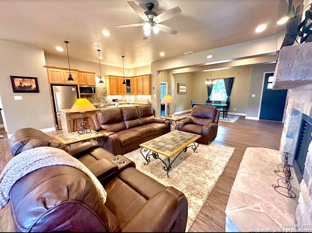 living area featuring baseboards, recessed lighting, dark wood-style floors, and ceiling fan with notable chandelier