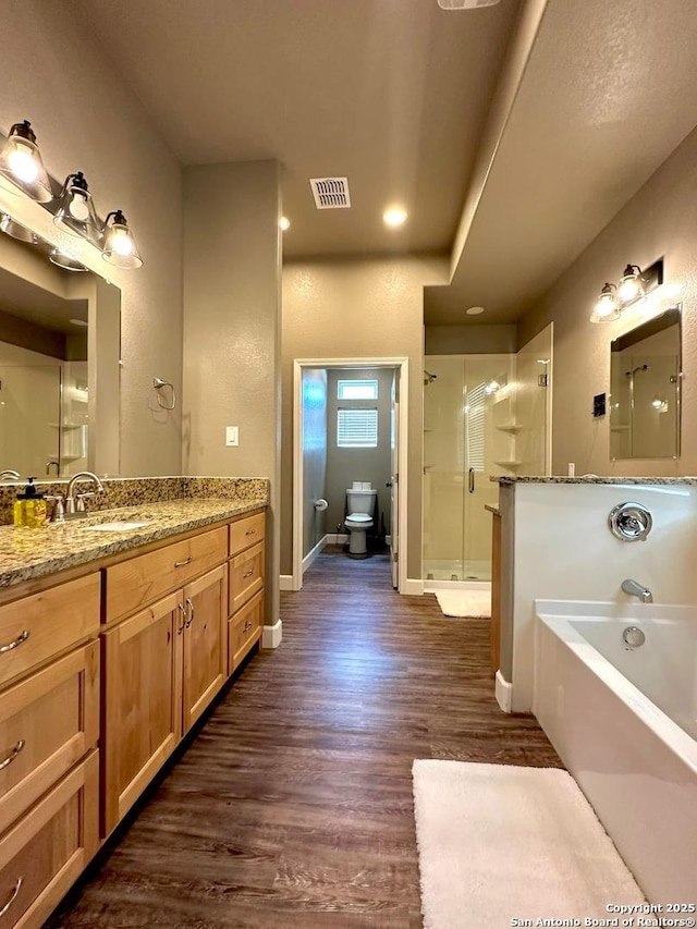 full bathroom featuring toilet, a bath, a shower stall, vanity, and wood finished floors