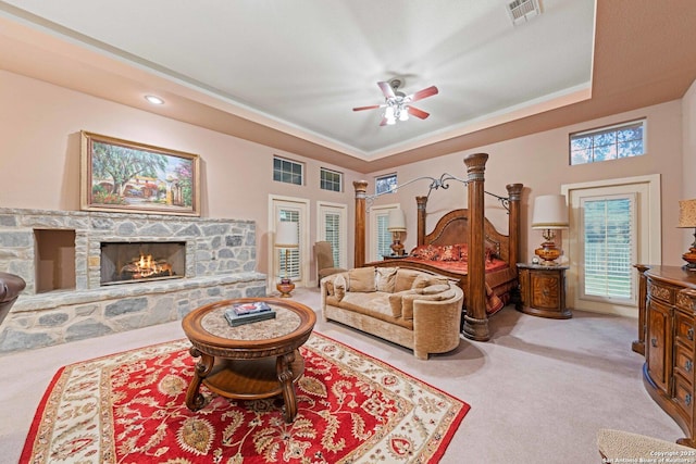 26118 Alto Oaks, San Antonio, TX 78255 - bedroom with light carpet, a tray ceiling, a stone fireplace, and a ceiling fan