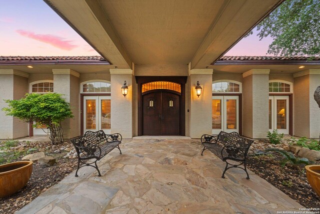 26118 Alto Oaks, San Antonio, TX 78255 - exterior entry at dusk with a tile roof and stucco siding