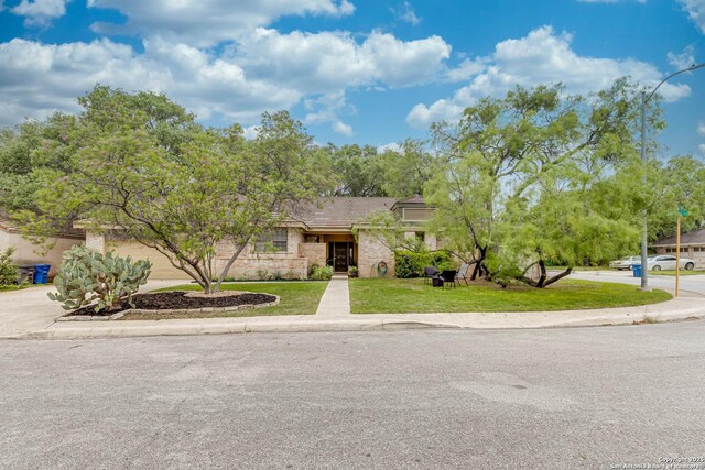 view of front of house with stone siding, driveway, and a front yard