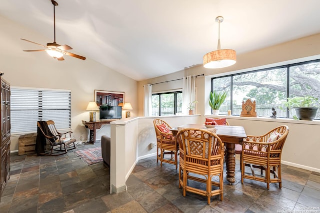 dining area featuring vaulted ceiling, stone tile floors, baseboards, and ceiling fan