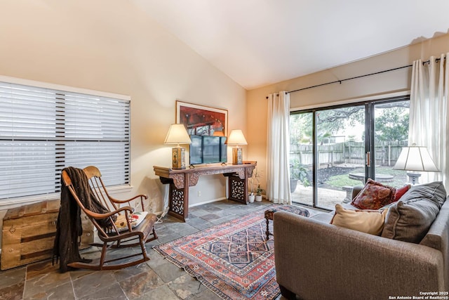 living area with high vaulted ceiling, baseboards, and stone finish floor