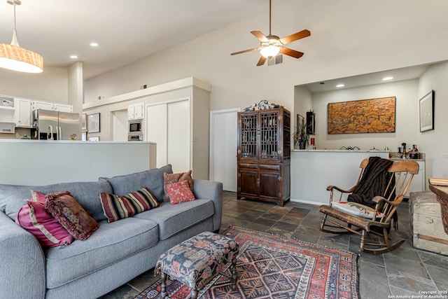 living area with recessed lighting, high vaulted ceiling, ceiling fan, and stone tile floors