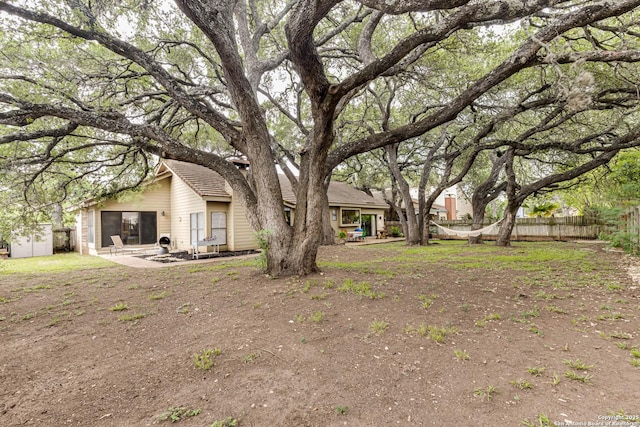 view of yard featuring fence, a patio, an outbuilding, and a storage shed