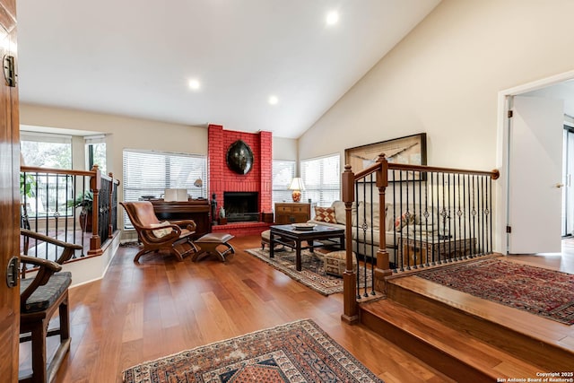 living room featuring a fireplace, recessed lighting, high vaulted ceiling, and wood finished floors