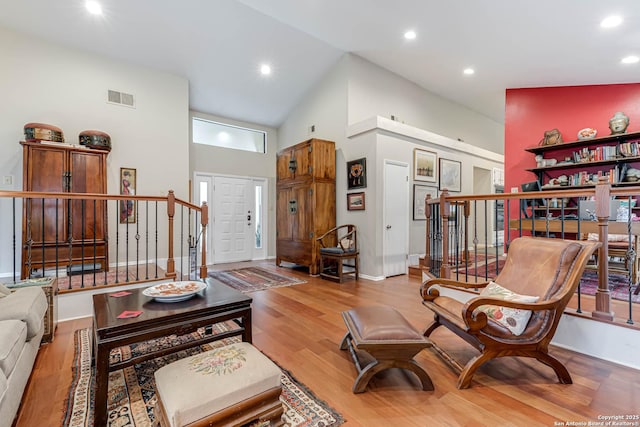 living area with wood finished floors, high vaulted ceiling, recessed lighting, visible vents, and stairs
