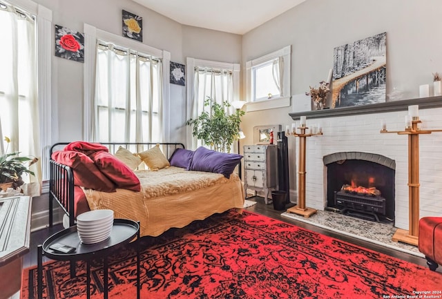 bedroom featuring wood finished floors and a brick fireplace