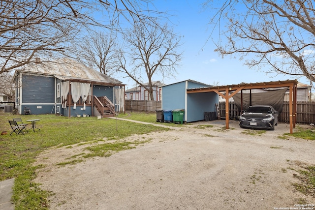 exterior space with dirt driveway, a detached carport, and fence