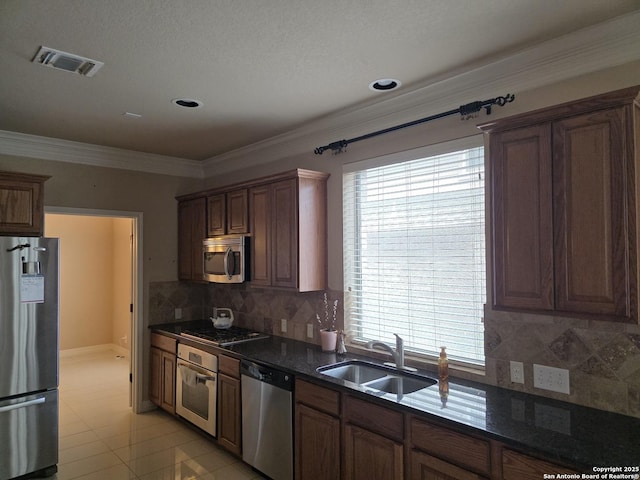 kitchen with ornamental molding, visible vents, a sink, stainless steel appliances, and tasteful backsplash
