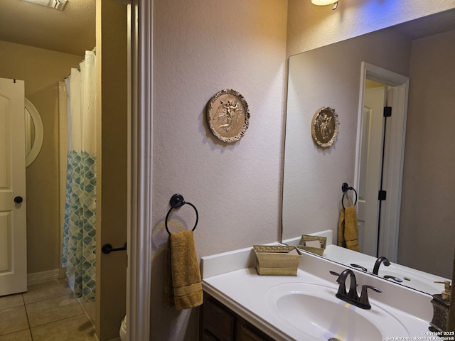 bathroom with tile patterned flooring, curtained shower, a textured wall, and vanity
