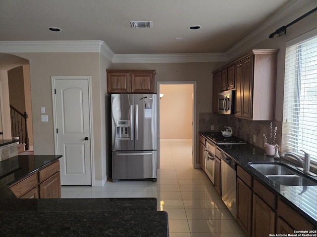 kitchen featuring light tile patterned floors, appliances with stainless steel finishes, a sink, and arched walkways