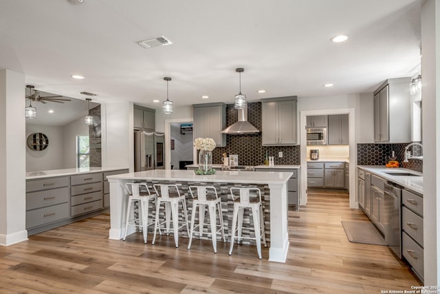 1397 Desert Gold, Boerne, TX 78006 - kitchen featuring gray cabinetry, a sink, wall chimney range hood, stainless steel appliances, and a kitchen breakfast bar